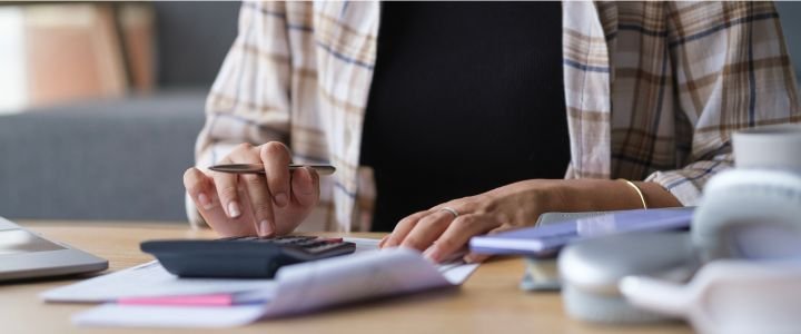 Woman using calculator, counting monthly budget, household expenses, rental fees, paying bills online.